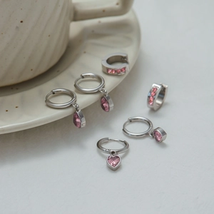 Detailed view of silver titanium steel earrings with pink heart and teardrop pendants