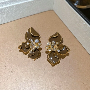 Detailed macro shot of caramel enamel flower earrings with crystal center and gold edges