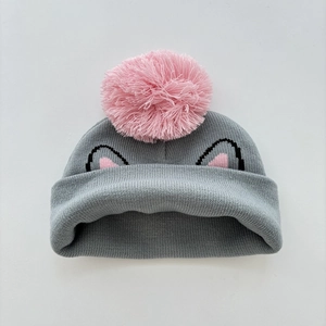 Close-up of gray knit hat featuring pink pom-pom and cat ear embroidery detail