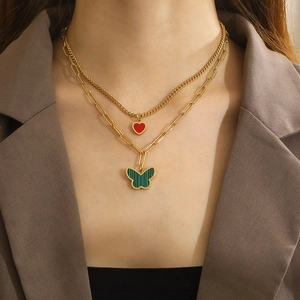 Close-up of double-layer necklace with red heart and green butterfly on a model