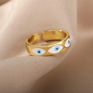 Detailed close-up of 18K gold evil eye ring with blue enamel on silk fabric
