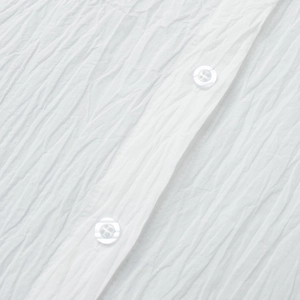 Detailed macro view of white pleated shirt fabric with premium button closure texture