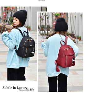 Detail of waterproof oxford fabric backpacks in black and burgundy with bear charms