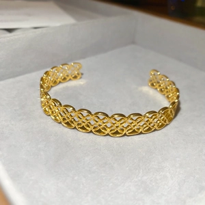 Gros plan du bracelet jonc doré à fleurs ajourées dans un écrin en velours gris