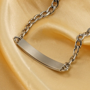 Macro view of silver cuban chain bracelet featuring a brushed rectangular metal ID plate