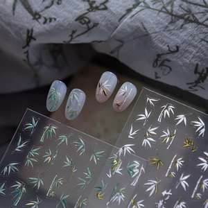 Detail of bamboo nail stickers with white and green leaf patterns and metallic accents