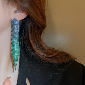 Close-up of long tassel earrings with blue to green gradient rhinestones on model