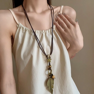 Detail der Vintage-Boho-Halskette mit Bronze-Stern und Blattanhängern an Wachskordel