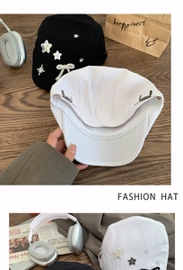Detail of star patches and bow on black and white cotton beret hats for women
