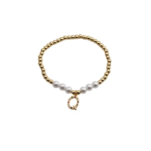 Detail of gold beaded bracelet with white pearls and a colorful zircon letter Q charm