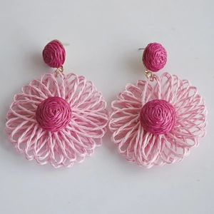 Detail of handmade raffia flower earrings in pink and rose tones for summer style