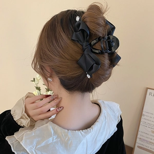 Detail of a large black satin bow hair claw with rhinestones worn for a half-up hairstyle