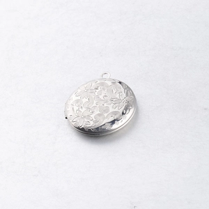 Macro detail of oval 316L stainless steel locket with vintage floral engraving