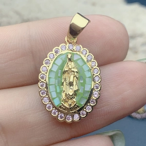 Detail shot of the oval Guadalupe Mary pendant, featuring a green mosaic background and pink zircon halo.