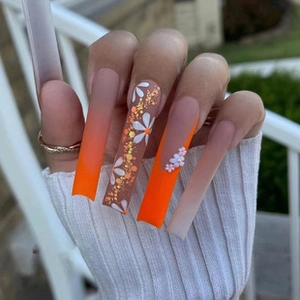 Detailed view of long square press-on nails with orange gradient and 3D floral accents