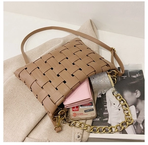 Macro view of woven leather bag interior showing phone, wallet and gold chain strap