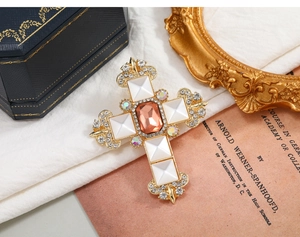 Detailed close-up of a vintage cross brooch with amber stone and baroque engravings