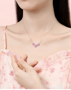 Close-up of pink zircon flower pendant on a sterling silver chain worn by a model