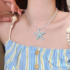 Close-up of a light blue starfish pendant necklace with white beads on a model's neck