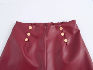 Détail de la taille en similicuir bordeaux avec boutons dorés et texture fine