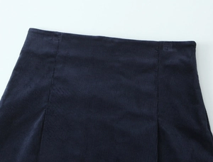 Detailed close-up of dark blue corduroy fabric texture and waist stitching on the mini skirt