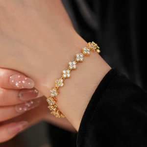 Gros plan d'un bracelet trèfle doré serti de zircons sur le poignet d'un mannequin
