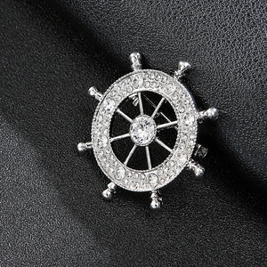 Close-up of a silver ship wheel brooch with sparkling rhinestones on black leather