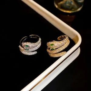 Snake wrap open rings in gold and silver plating with white micro-zirconia and green eyes