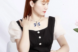 Close-up of a silver dragonfly pendant necklace with blue crystal inlay on a model