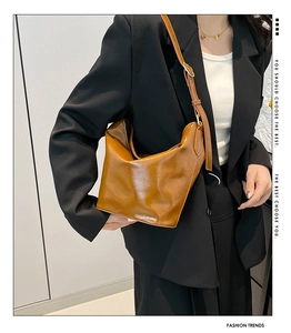 Close-up of caramel PU leather bucket bag with vintage pleated texture and shoulder strap