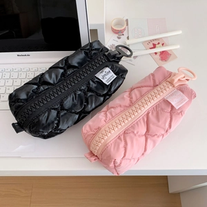 Close-up of quilted cream style pencil cases in pink and black with oversized zippers