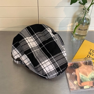 Detail of black and white checkered flat cap with vintage embroidery on metal surface