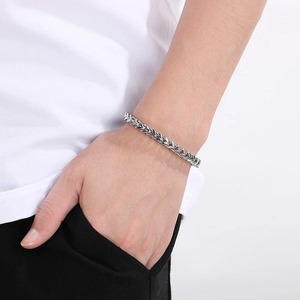 Close-up of a silver wheat chain bracelet worn on a wrist for a minimalist unisex look