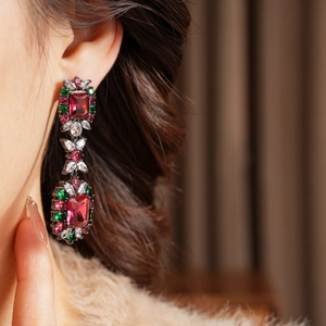 Close-up of vintage drop earring with red gemstone and green zircon on model