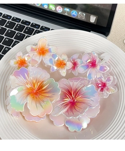 Detail of gradient plumeria hair claw clips with iridescent finish on a white tray