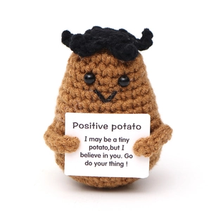 Close-up of a crocheted positive potato holding a card with an inspirational message