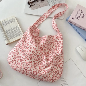 Flat lay of pink heart leopard print canvas tote bag with books and daily accessories