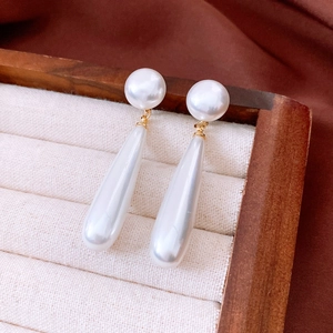 Detailed macro shot of vintage pearl drop earrings in a premium velvet jewelry display case