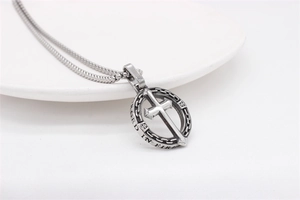 Gros plan du pendentif croix argentée vintage avec gravure Forged in Fire sur acier