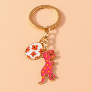 Close-up of pink dinosaur and floral egg charms on a gold keychain with colorful details
