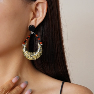 Vintage teardrop resin earrings with gold foil and bead accents on a model profile