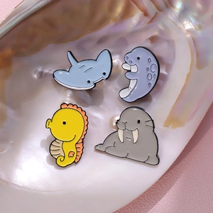 Set of four colorful enamel ocean animal pins featuring manta ray, seahorse, and walrus
