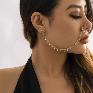 Detail of gold nose-to-ear chain jewelry featuring crescent moon pendants on a link chain