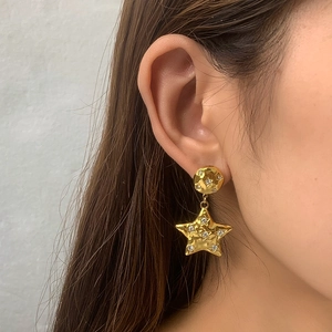 Detail of 14k gold plated star earrings with hammered texture and sparkling rhinestones