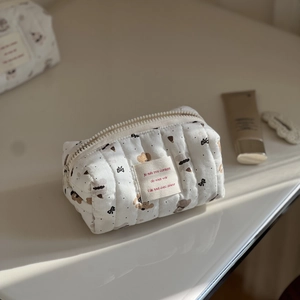Detailed view of a white quilted cotton makeup bag featuring cute brown bear patterns