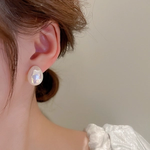 Gros plan d'une boucle d'oreille goutte en perle baroque portée par un mannequin