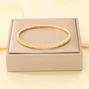 Primo piano di un bracciale rigido in acciaio inossidabile dorato con texture a coste