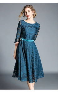 Detail of elegant dark peacock green lace dress with floral embroidery and satin belt