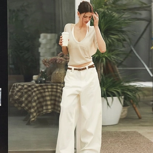 Detail of light beige V-neck sun protection top with high-waisted wide-leg white pants
