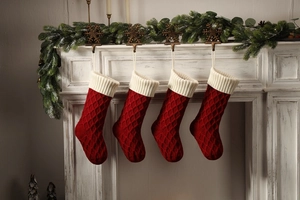 Nahaufnahme roter Strick-Weihnachtssocken mit weißen Bündchen an einem weißen Kamin